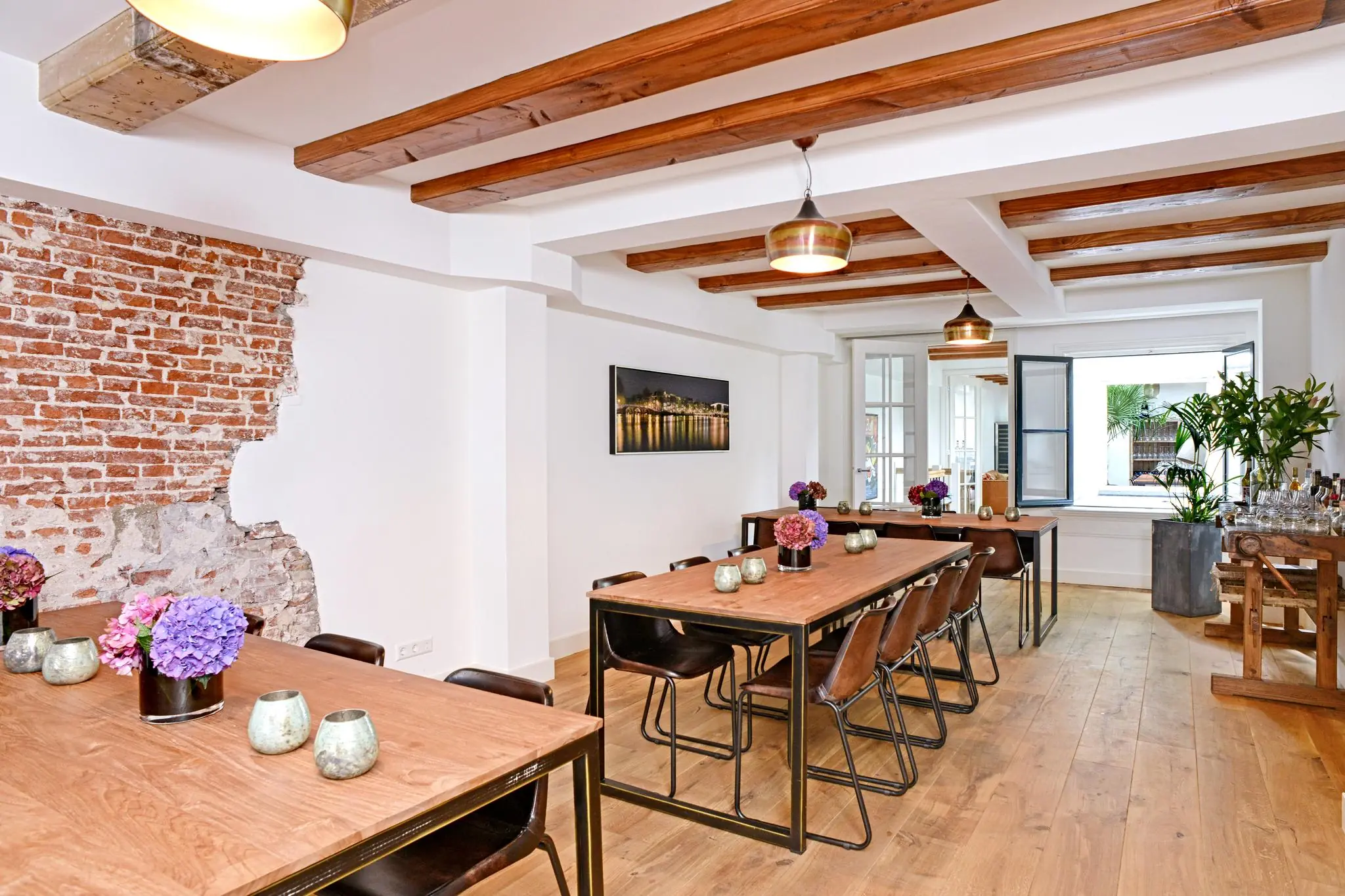 Licht en stijlvol ingericht vergaderruimte aan de Nieuwe Kerkstraat met houten details, bakstenen muuraccent en bloemendecoratie.